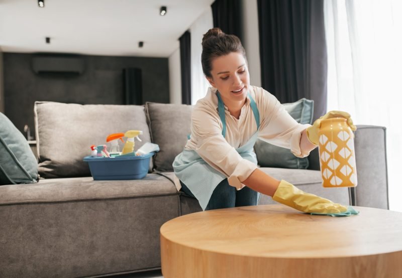 Chores. A woman cleaning a table surfcase with disinfector